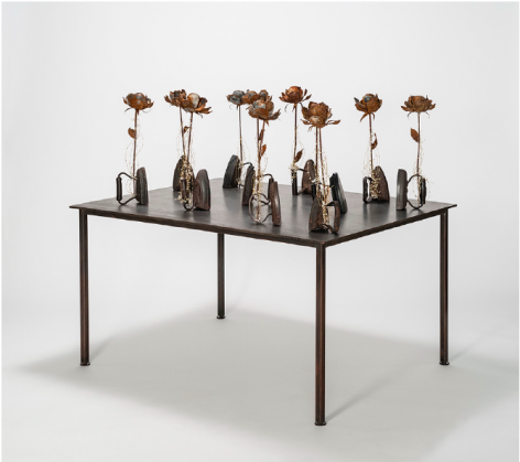 Karin Broker  First Wives, 2018  11 antique irons, wired metal roses with crystals on steel table  44.5 x 48 x 36 inches  Inquire
